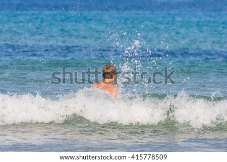 Young boy on the beach  having fun with the waves