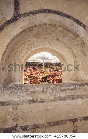 Arch framing Cesky Krumlov - Czech medieval town viewed through a loop-hole window in a castle wall. Vertical composition.