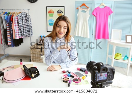 Young female blogger with makeup cosmetics recording video at home Royalty-Free Stock Photo #415804072