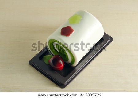 Fancy soap in roll cake form with cherry on wooden board
