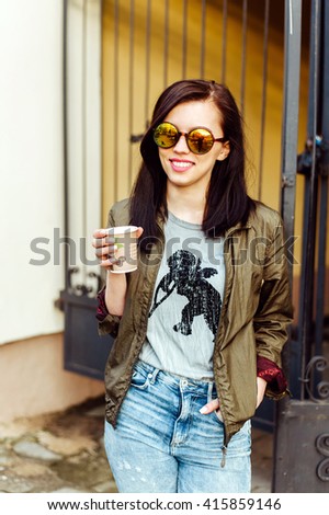 A young girl walks through the streets in colorful sunglasses. Drink coffee and drinking smile
