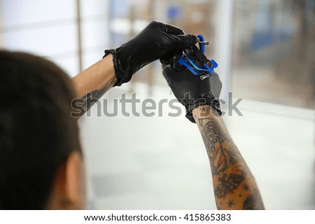 Man holding tattoo machine on blurred background