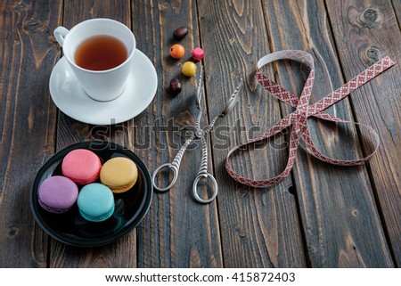 Colorful macaroons with tea on old wooden background