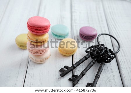 Macaroons with key on wooden table.