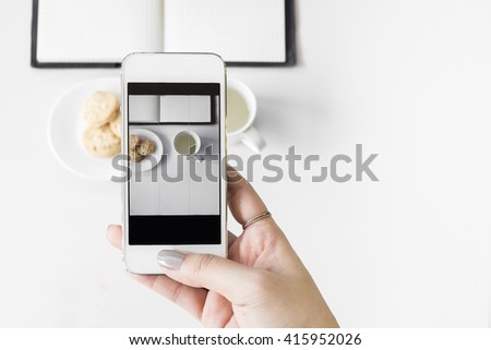 Top view of a female hand taking picture with a smartphone, focuses on the hand holding the phone