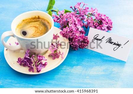 Lilac flowers and cup of coffee with good morning note on rustic wooden background
