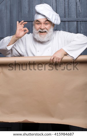 Cook holding parchment paper brown color on wooden background, copy space