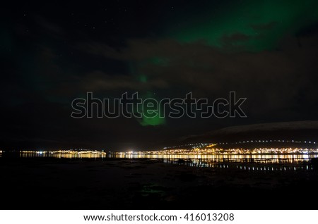 aurora borealis, northern lights over snowy mountain, reflective fjord water and whale island in northern norway in late autumn