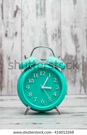 Green retro alarm clock on white wooden background