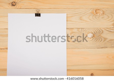 Black clip and White blank note paper hang on wood pane