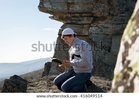Muslim reads the Koran under the blue sky on the mountain
