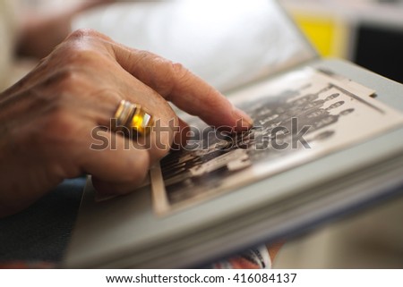 Senior woman's hand touching an old photo. Close up.