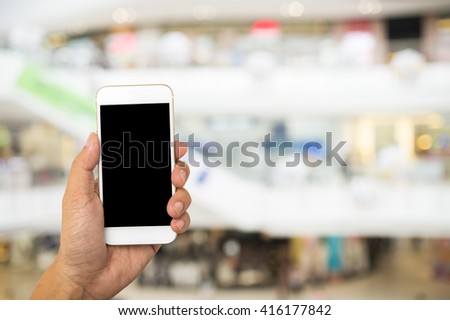hand and smart phone on blurred of shopping mall
