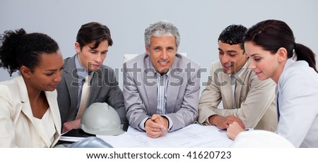 Smiling architect manager in a meeting with his team studying plans