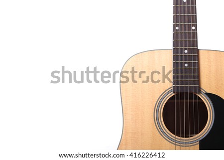 Acoustic guitar standing against white wall background.