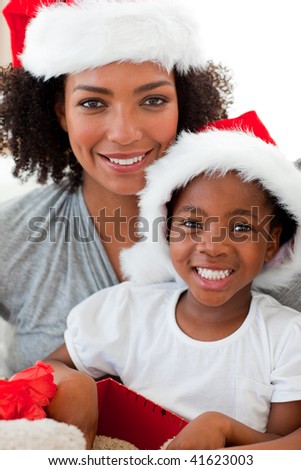 Smiling Afro-American mother and daughter opening a Christmas gift