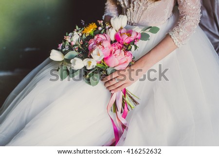 wedding bouquet with pink tulips, berries and ribbons  in hands of the bride Royalty-Free Stock Photo #416252632