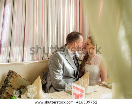 Beautiful Russian bride and groom embracing in a restaurant on a background of curtains