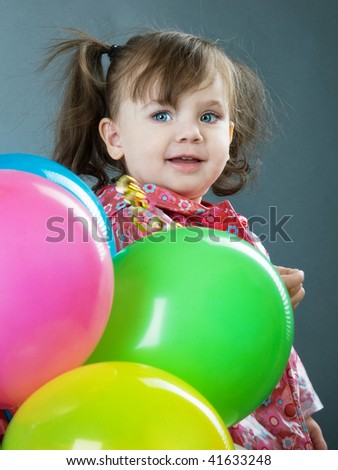 little girl holding colorful balloons on a grey background
