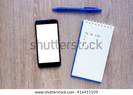 Notepad with Empty to do list, smart phone and Pen on Wooden Background