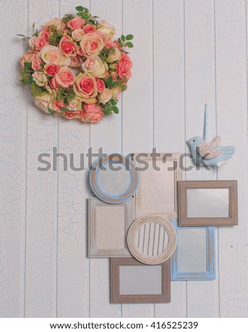 photo frames, toy bird and flowers on wooden background in blue tones