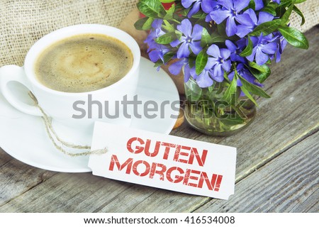 Coffee mug with Vinca flowers and notes Guten Morgen - good morning in German. filter sunlight, toned image.
