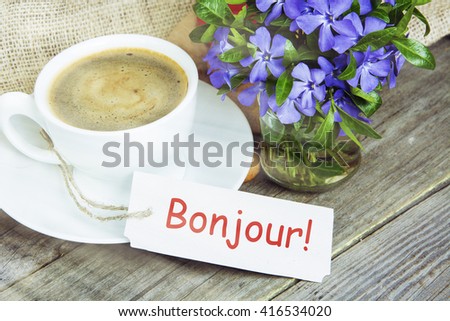 Coffee mug with Vinca flowers and notes bonjour- good morning in French. filter sunlight, toned image.