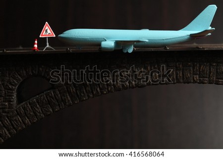 Blue color jet plane toy model with miniature figure maintenance equipment model put on the model toy bridge represent the transportation and airplane repair concept related idea.