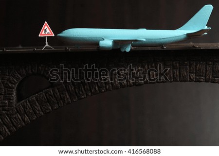 Blue color jet plane toy model with miniature figure maintenance equipment model put on the model toy bridge represent the transportation and airplane repair concept related idea.