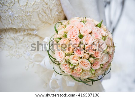 Round bouquet of pale pink roses on a background of a wedding dress