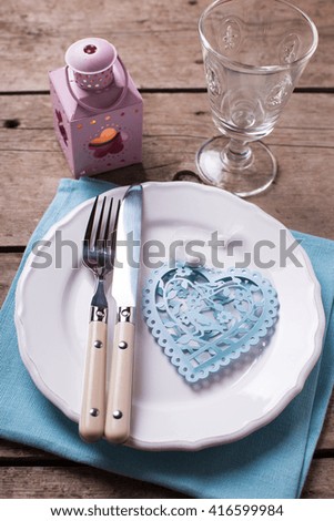 Summer  table setting. Decorative heart, knife and fork on white plate on vintage wooden background. Selective focus.