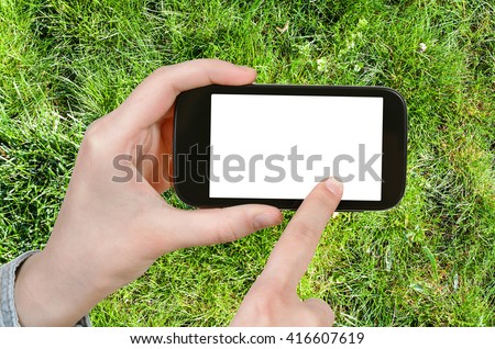 gardening concept - farmer photographs green grass of lawn on smartphone with cut out screen with blank place for advertising