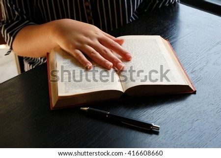 women read book on wooden table ,hand writing pen on paper page,hardworking for achievement business target concept, reading book for knowledge concept. 