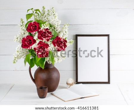 Lilac bouquet with roses in clay jug with motivational frame  for your text or picture on background of white wooden planks in scandinavian style