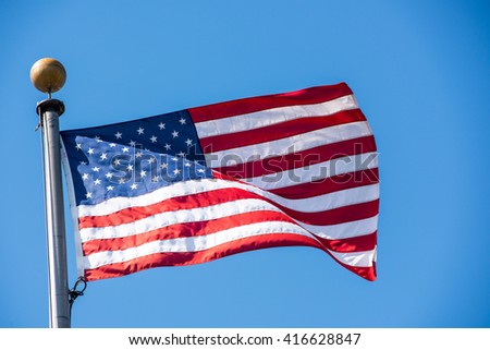 American flag waving with the wind on a clear blue sky.
