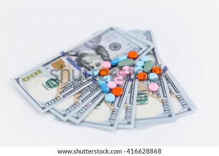 Closeup of colorful pills and dollar banknotes on white surface