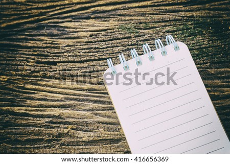 the note book with the wooden background in vintage effect