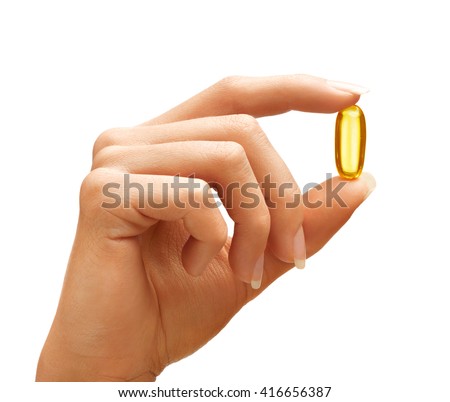 Woman's hand holding Omega 3 capsule isolated on white background. Close up. High resolution product.