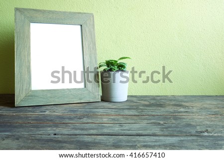 frame with plant pot on old wooden table and green wall background