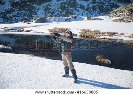 brunette woman with green, red and brown clothes with camera, as photographer taking selfie photo picture, in winter snow Gredos mountain, Avila, Spain, Europe