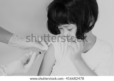 Gloved hand of nurse making an injection to little girl on yellow background