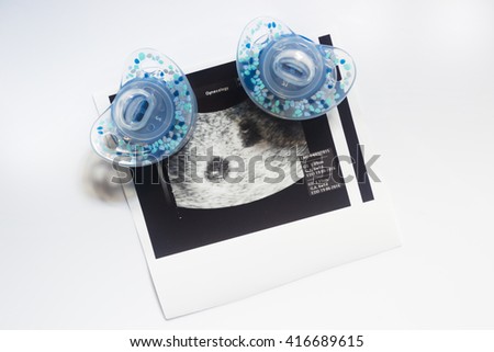 Twin pregnancy ultrasound. Two soothers and an ultrasound picture of two babies.