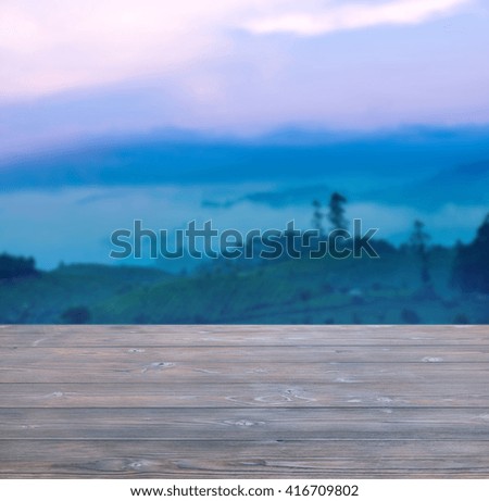beautiful landscape of trees and fog in pre-dawn haze with wooden empty table in India, Kerala, Munnar