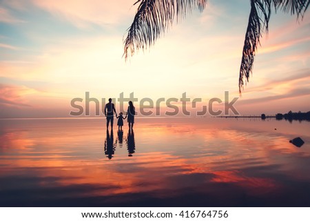 Beautiful sunset landscape with silhouettes of family at the sea