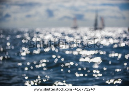 Beautiful abstract background bokeh sun light reflections on blue aqua water sailing boat
