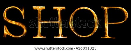 Wooden letters in gold on black background spelling SHOP