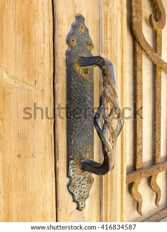 Old ornamental rusty metal door handle on a wooden door. Photo taken  in Jaffa, Israel.