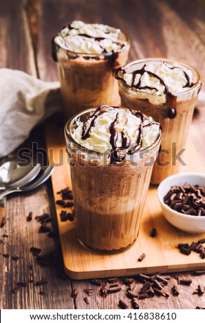 Homemade coffee cocktail with whipped cream and liquid chocolate on rustic wooden background 