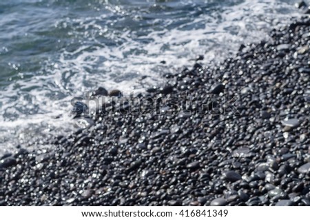 Blurred image of wet stony coast and sea wave