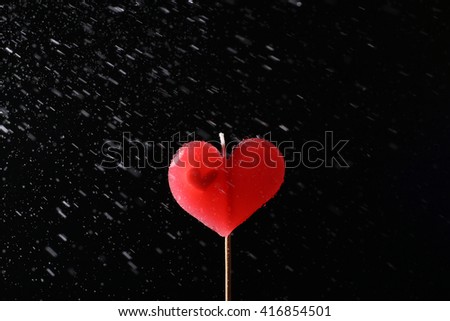 Heart  candle with water spray on black background - concept  heart in rains